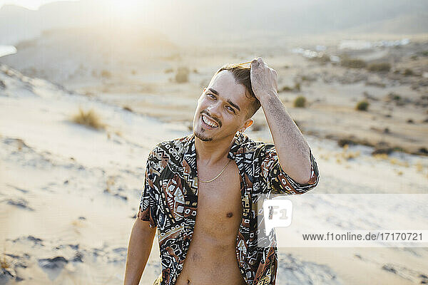 Glücklicher junger Mann mit Hand im Haar in der Wüste von Almeria  Tabernas  Spanien