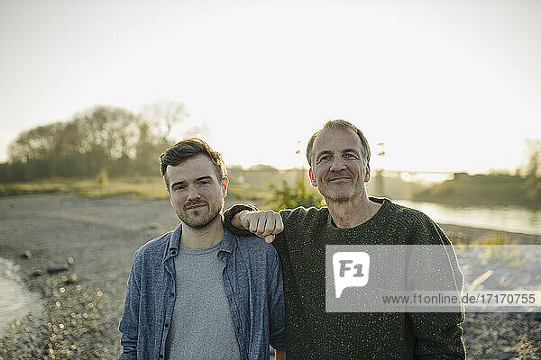 Smiling father and son against clear sky at evening