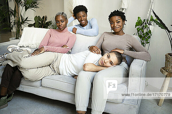 Smiling female friends on sofa in living room at home