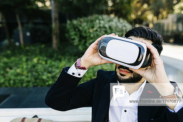 Businessman using virtual reality simulator while sitting outdoors