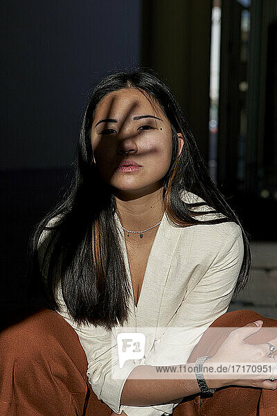 Beautiful young woman crouching with hand shadow on face