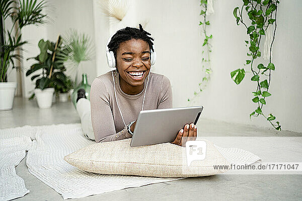 Young businesswoman laughing while using digital tablet in living room