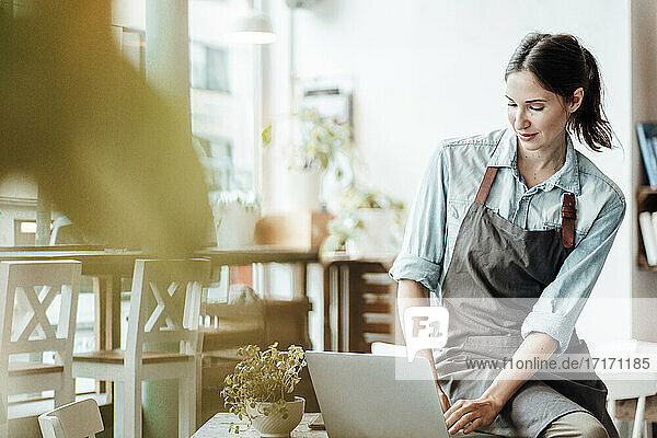 Female entrepreneur working on laptop at coffee shop