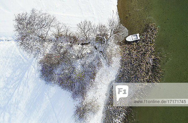 Boat moored at Irrsee by snow covered land during winter