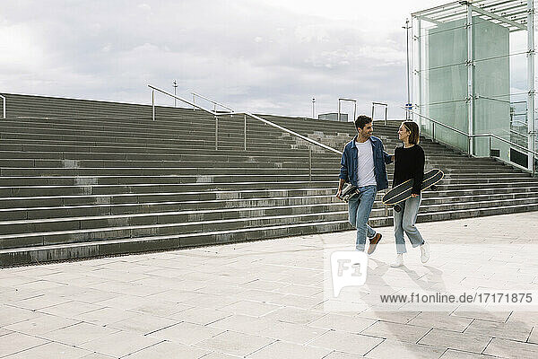Junges Paar mit Skateboards geht in der Nähe von Stufen