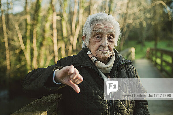 Unzufriedene ältere Frau mit Daumen-nach-unten-Geste im Winter