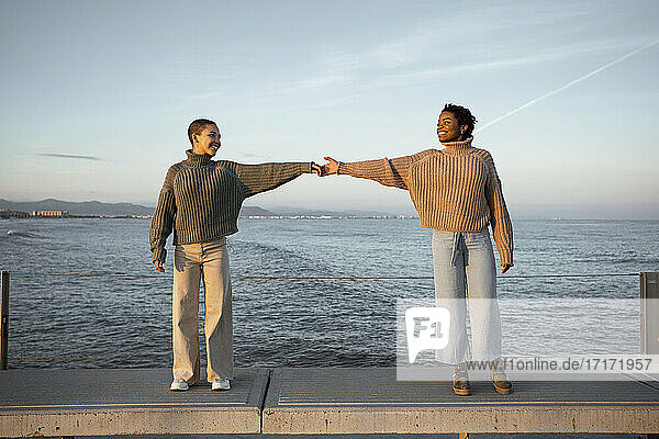 Freund streckt die Hände aus  während er auf einer Bank am Meer steht