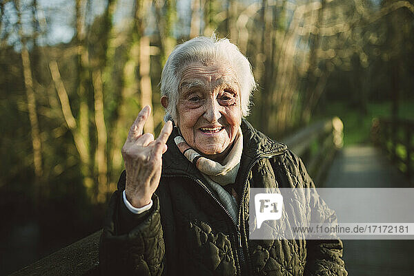 Fröhliche ältere Frau mit Hupzeichen an einem sonnigen Tag