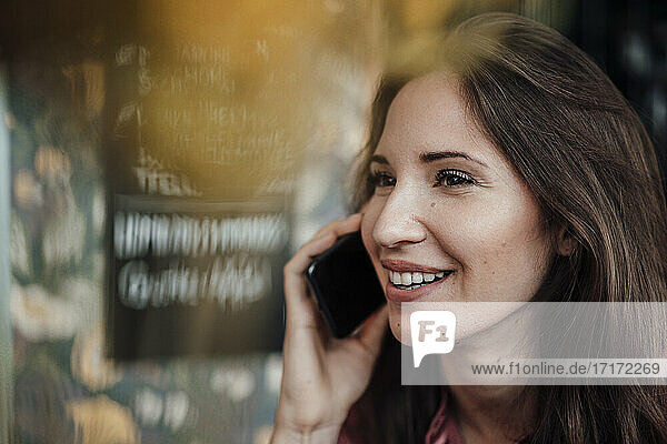 Female professional smiling while talking on smart phone at cafe