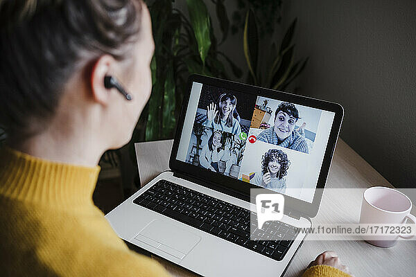 Young woman talking with friends over video conference on digital tablet while sitting at home