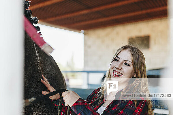 Fröhliche junge Frau mit Pferd auf dem Bauernhof