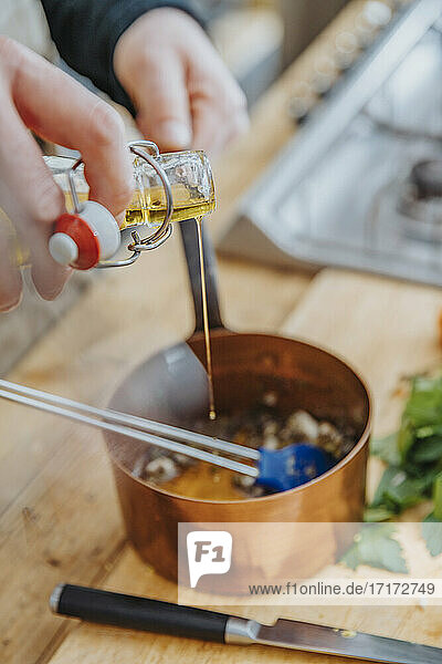 Close-up of chef pouring cooking oil in saucepan in kitchen