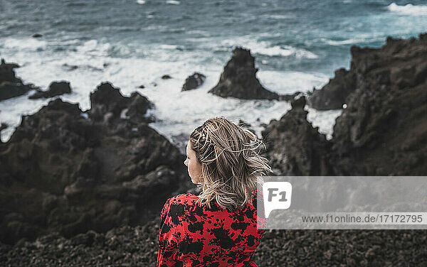 Junge Frau mit Blick auf das Meer  während sie in Los Hervideros  Lanzarote  Spanien steht