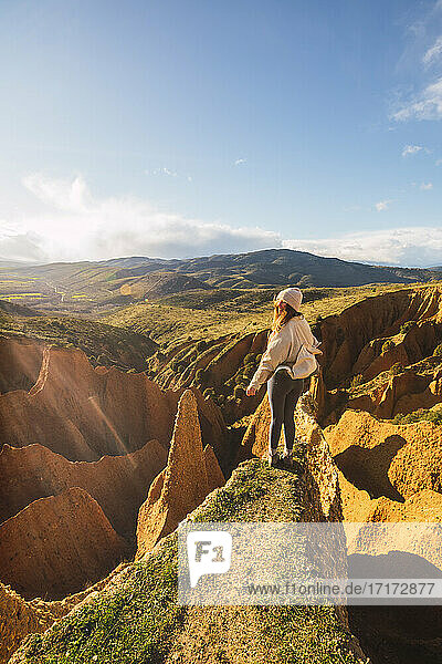 Unbekümmerte junge Frau  die auf einer Felsformation vor dem Himmel in Valdepenas de la Sierra  Spanien  steht