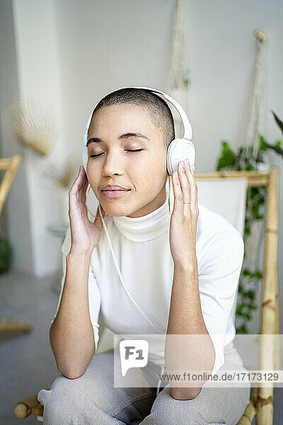 Young woman listening music through headphones in living room