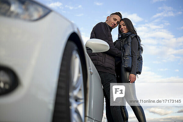 Selbstbewusstes Paar starrt beim Stehen neben dem Auto in den Himmel