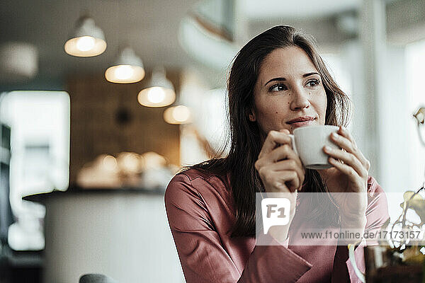 Geschäftsfrau mit Kaffeetasse in der Hand und nachdenklich in einem Cafe
