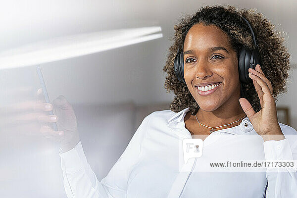 Woman wearing headphones looking away while sitting at home