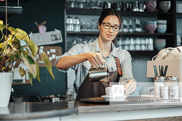 Female owner pouring coffee in cup at cafe