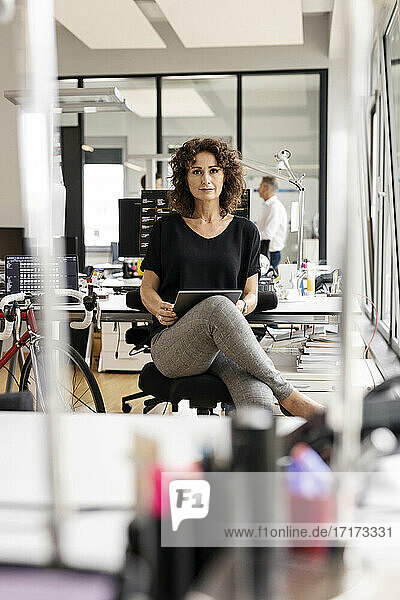 Selbstbewusste Geschäftsfrau mit digitalem Tablet im Büro sitzend