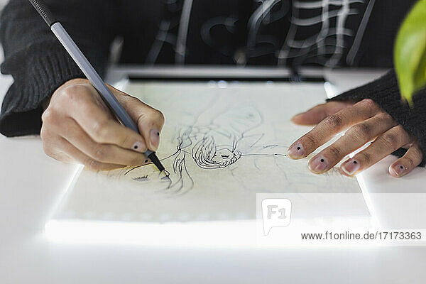 Female design professional drawing on paper at studio