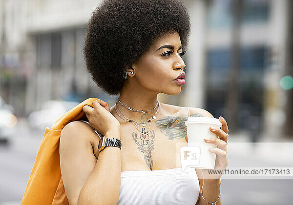 Afro woman with coffee cup outdoors