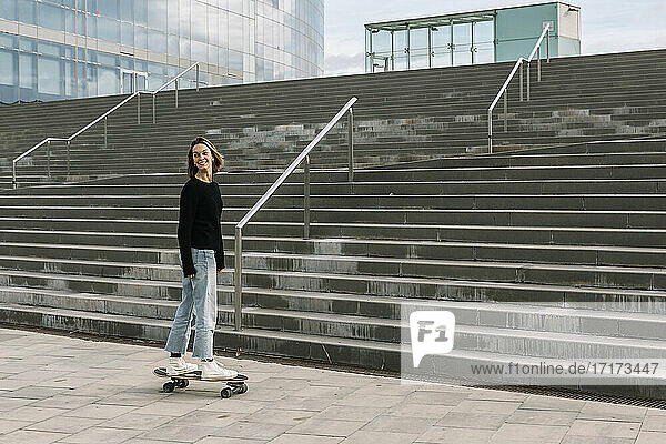 Junge Frau auf dem Skateboard in der Nähe der Treppe