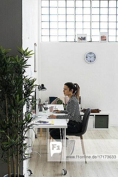 Unternehmerin arbeitet am Computer  während sie im Büro sitzt