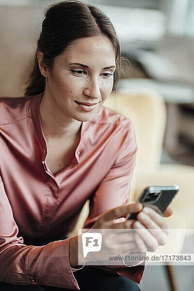 Female entrepreneur using mobile phone at coffee shop
