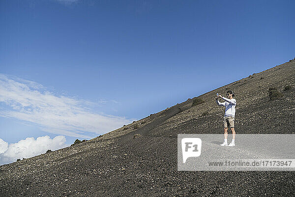 Young male tourist photographing while standing on El Cuervo Volcano  Lanzarote  Spain