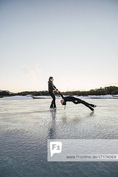 Two female figure skaters performing death spiral on frozen lake