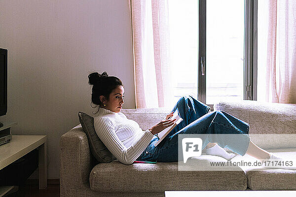 Young woman reading on sofa