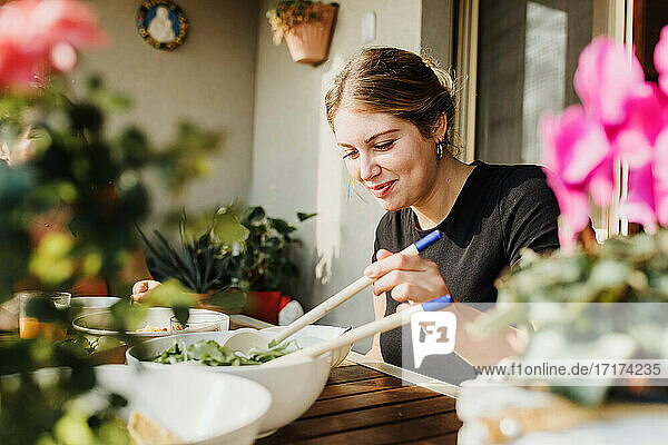Junge Frau serviert Salat