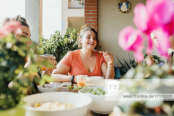 Junge Frau beim Essen auf dem Balkon