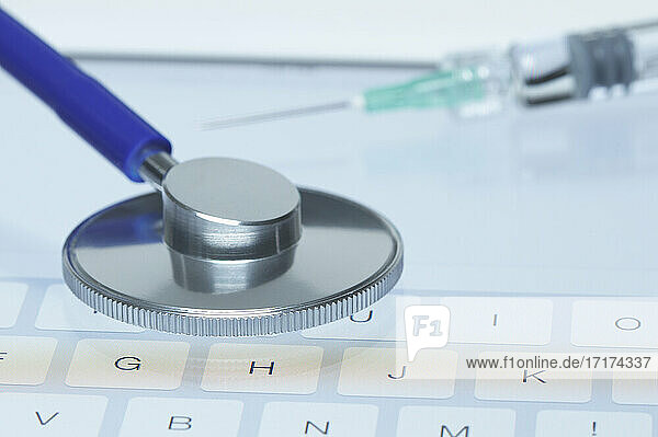 Online-Medizin. Bruststück eines akustischen Stethoskops und eine Spritze auf dem Bildschirm eines Tablet-Computers