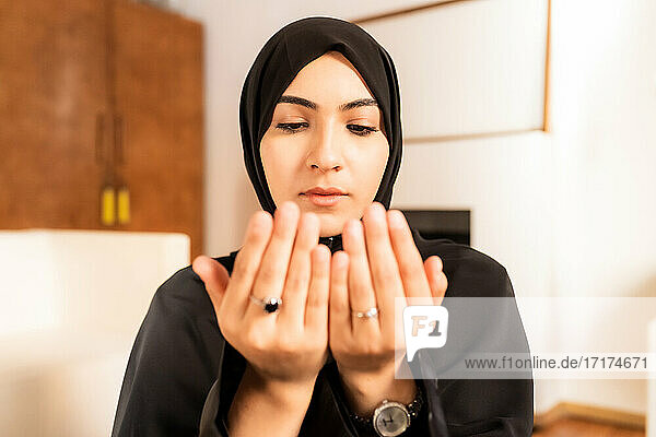 Junge muslimische Frau mit zusammengelegten Händen beim Gebet
