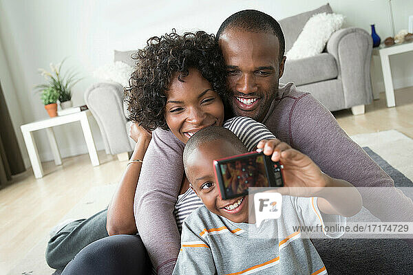 Eltern und Sohn fotografieren sich selbst mit einer Digitalkamera