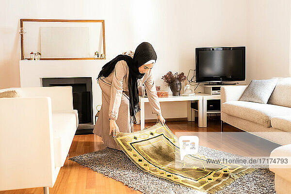 Junge muslimische Frau bereitet die Gebetsmatte vor