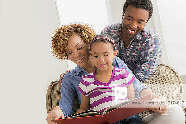 Eltern mit Tochter  die ein Buch liest