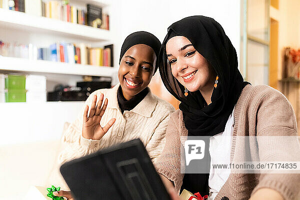 Zwei junge muslimische Frauen benutzen ein Tablet für einen Anruf
