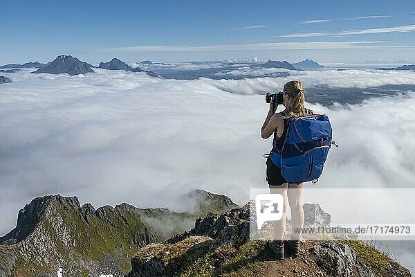 Wanderin blickt über Berglandschaft im Nebel  Blick vom Gipfel des Stornappstinden  Lofoten  Nordland  Norwegen  Europa