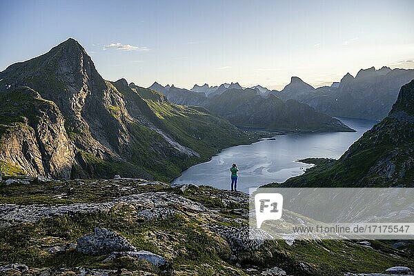Hiker looking at mountain landscape with fjord Forsfjorden  Moskenesöy  Lofoten  Nordland  Norway  Europe