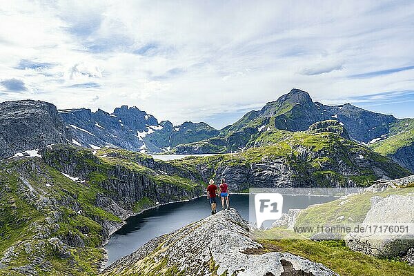 Zwei Wanderer blicken über See Tennesvatnet  Berglandschaft  Moskenesöy  Lofoten  Nordland  Norwegen  Europa