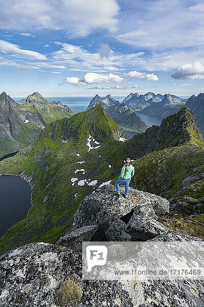 Young woman looking over mountain landscape with lake Tennesvatnet  view from the top of Munken  Moskenesöy  Lofoten  Nordland  Norway  Europe