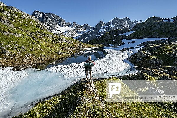 Young woman  hiker at a lake  mountains and snow  hiking to Trollfjord Hytta  at Trollfjord  Lofoten  Nordland  Norway  Europe