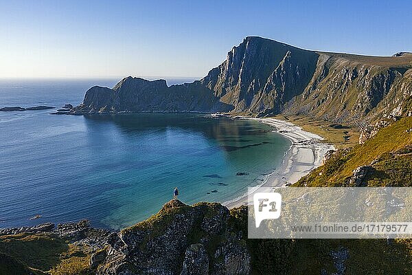 Hiker standing at the precipice  cliffs  beach and sea  in the back peak of the mountain Måtinden  near Stave  Nordland  Norway  Europe
