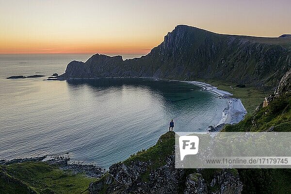 Evening mood  hiker on rocks  cliffs  beach and sea  in the back summit of the mountain Måtinden  near Stave  Nordland  Norway  Europe