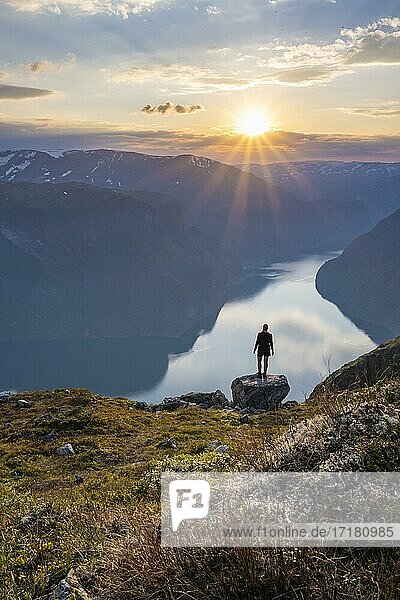 Wanderin genießt Ausblick  Sonnenuntergang am Gipfel des Berges Prest  Fjord Aurlandsfjord  Aurland  Norwegen  Europa