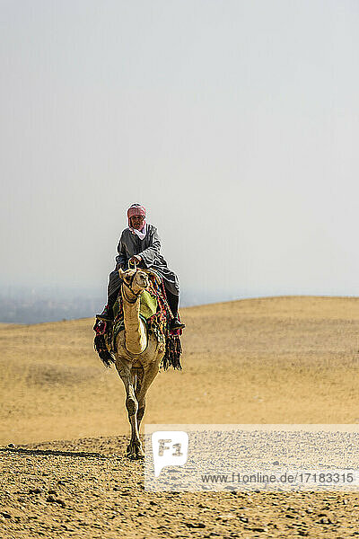 Man riding a camel in the desert outside Cairo