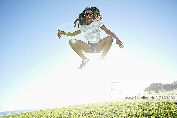 Junge gemischte Rasse Mädchen mit langen lockigen Haaren springt in der Luft